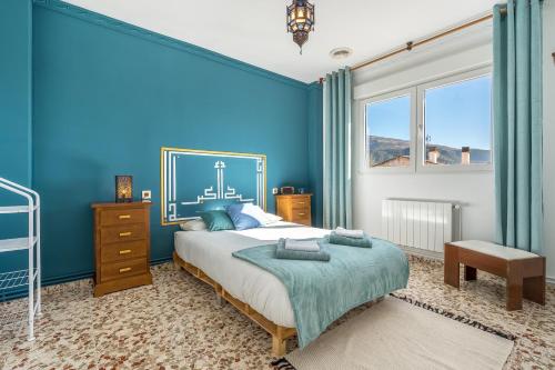 a blue bedroom with a bed and a window at Little Alhambra in Dúrcal