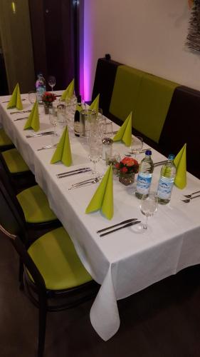 a long white table with green napkins and bottles of water at Hotel und Cafe Paso in Vierkirchen