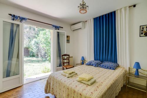 a bedroom with a bed with blue curtains and a window at Domaine du Courroussouve in Oppède