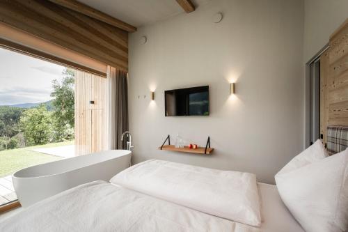 a bedroom with a tub and a bed and a window at Oberplunerhof Luxury Chalet Skyline in Chienes