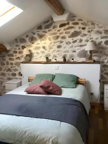 a bedroom with a large bed with a stone wall at Appartement de charme Saint-Romain in Saint-Romain