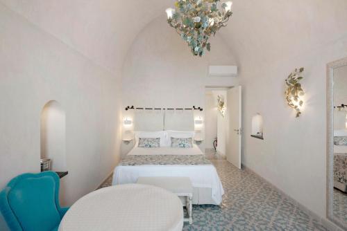 a white bedroom with two beds and a chandelier at Dimora elegante in Costa d'Amalfi in Conca dei Marini