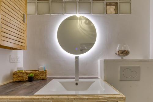 a sink in a kitchen with a round mirror at Sunny Day in La Grande Motte