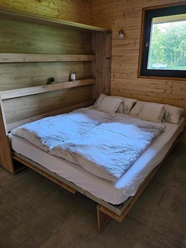 a large bed in a wooden room with a window at Weiherhüttla in Untersteinach
