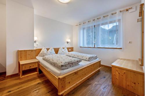 a bedroom with a wooden bed and a window at Maurerhof Morgenrot in Maranza