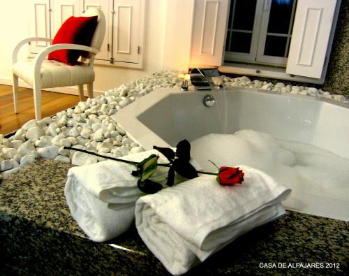 ein Badezimmer mit einer Badewanne, Handtüchern und einem Stuhl in der Unterkunft Casa de Alpajares - Guest House & Spa in Freixo de Espada à Cinta