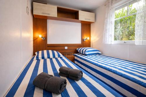 two beds sitting next to each other in a bedroom at Bungalow Camping 4 étoiles - Mer à pied in Hyères