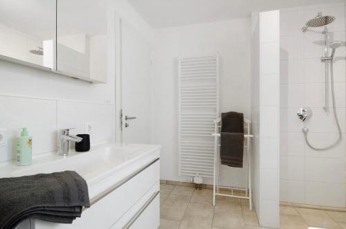a white bathroom with a shower and a sink at Ferienhaus Aura in Bodman-Ludwigshafen