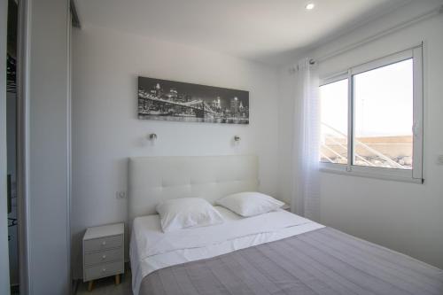 a white bedroom with a bed and a window at Sublime Appart Neuf in Albitreccia