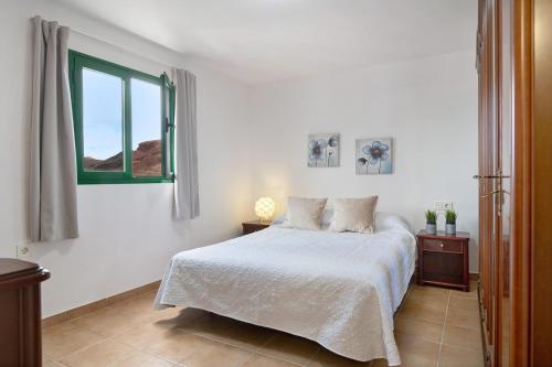 a white bedroom with a bed and a window at San roque in Tinajo