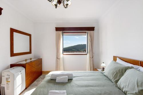 a bedroom with a large bed with a window at Casa Cimo D'Aldeia in Vila Cova de Perrinho