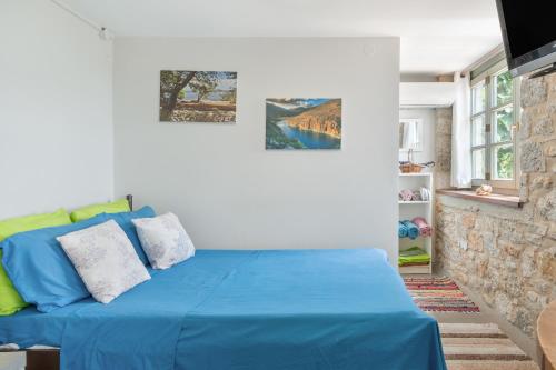 a bedroom with a blue bed with two pictures on the wall at Boutique Stone Cottage House in Kalymnos
