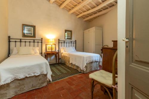 a bedroom with two beds and a chair at Casa rural siglo xviii in Pals