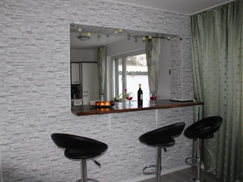 a mirror on a brick wall with two black stools at Ferienwohnung Möhneblick in Möhnesee