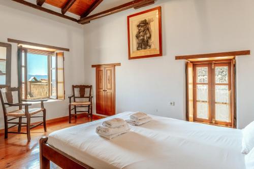 a bedroom with a bed and a chair and windows at Casa Tradizionale Monemvasia in Monemvasia