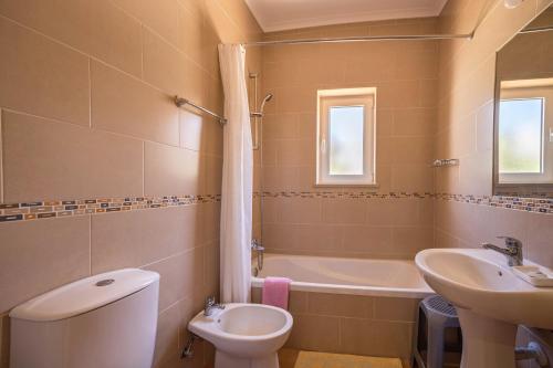 a bathroom with a sink and a toilet and a tub at Casa Bege T2 in Burgau