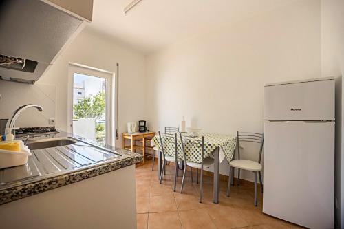 a kitchen with a table with chairs and a refrigerator at Casa Bege T2 in Burgau