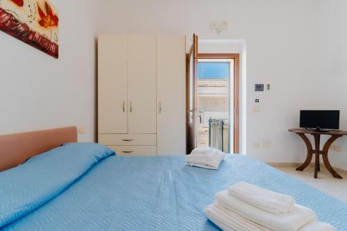 a bedroom with a blue bed with towels on it at La casetta 461 in Torre San Giovanni Ugento