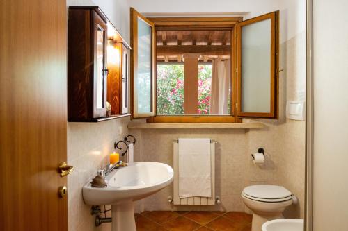 a bathroom with a sink and a toilet and a window at Bilo Anemone in Marina di Grosseto