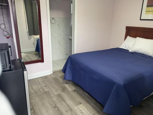 a bedroom with a blue bed and a television at Oshawa Inn Motel in Oshawa
