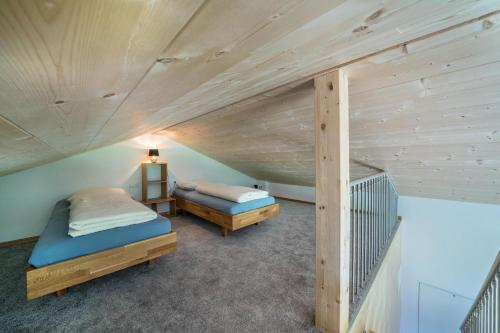 two beds in a room with wooden ceilings at Pixnerhof Chalet Natyra in Kastelbell-Tschars