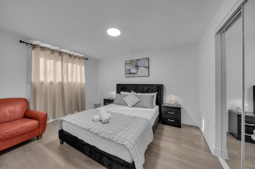 a bedroom with a bed and a red chair at Poolside Paradise minutes away from the Falls in Thorold