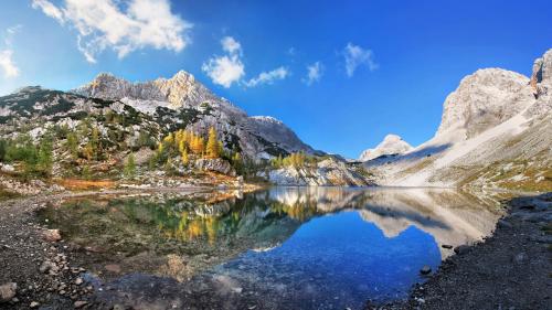 a mountain reflecting in a lake in the mountains at Apartments Bohinjskih 7 in Bohinj