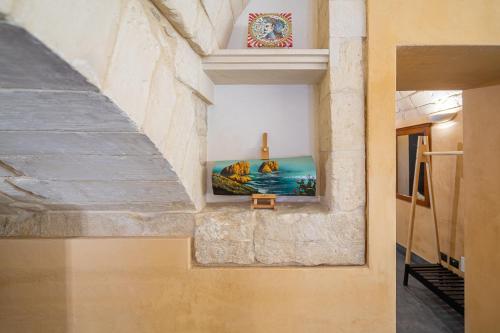 a room with a stone wall with a painting on the wall at Dammuso 3cirniechi in Ragusa