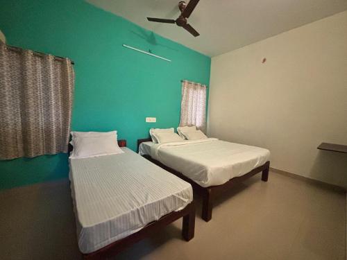 two beds in a room with a green wall at Thamira Residency Yercaud in Yercaud