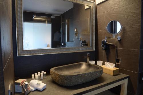 La salle de bains est pourvue d'un grand lavabo en pierre et d'un miroir. dans l'établissement Hôtel Chalet Royal, à Veysonnaz