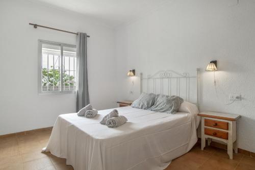 a white bedroom with a bed with towels on it at Complejo Alejandra in Conil de la Frontera