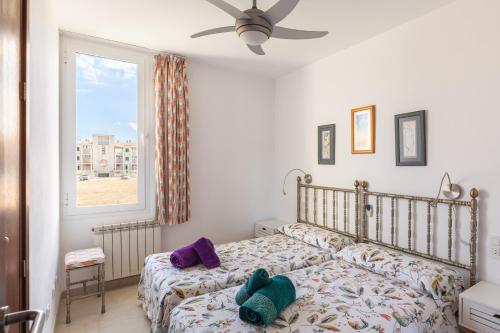 a bedroom with a bed with purple pillows and a window at Apartamento Llenaire cerca playa in Port de Pollensa