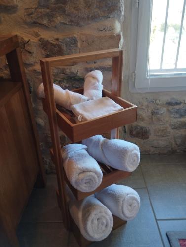a pile of towels on a shelf in front of a stone wall at Gîte SPA Sauna Piscine in Grospierres