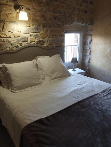 a bedroom with a large bed with a stone wall at Gîte SPA Sauna Piscine in Grospierres