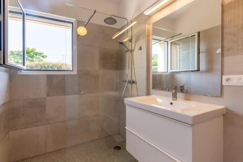 a bathroom with a sink and a shower and a mirror at Villa Luminières 2 in Sallelles