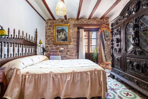 a bedroom with a large bed and a stone wall at Casa Retiro Vilafames in Vilafamés