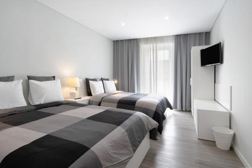 a hotel room with two beds and a flat screen tv at V L P Amorim in Ponta Delgada