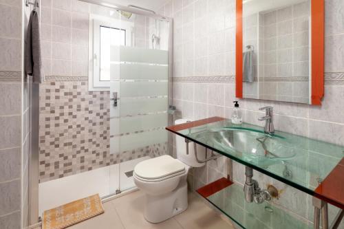 a bathroom with a toilet and a glass sink at Villa Pepa in Chilches