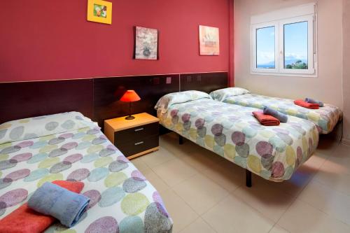 two beds in a room with red walls at Villa Pepa in Chilches