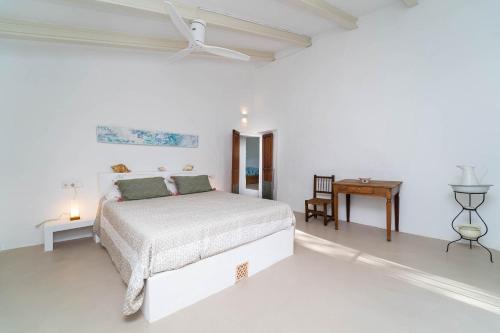 a white bedroom with a bed and a table at Se Taulera in Fornalutx