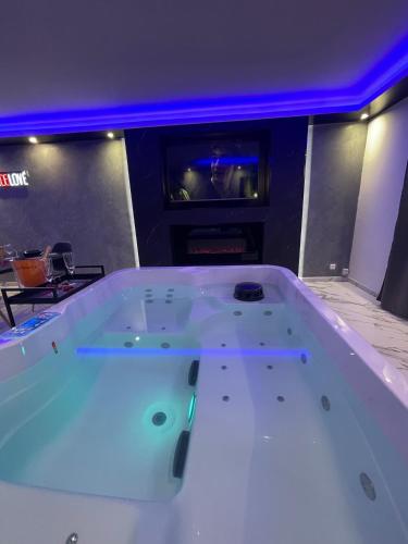 a large white bath tub in a room with a tv at La Casa de Lové Suite Jacuzzi in Melun