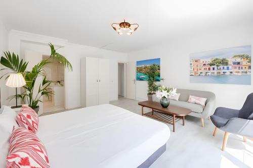 a white bedroom with a large bed and a couch at Tres Palmeras in Calas de Mallorca