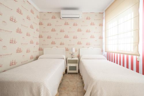 two beds in a room with white walls at Terraza Mar y Montaña in Nerja