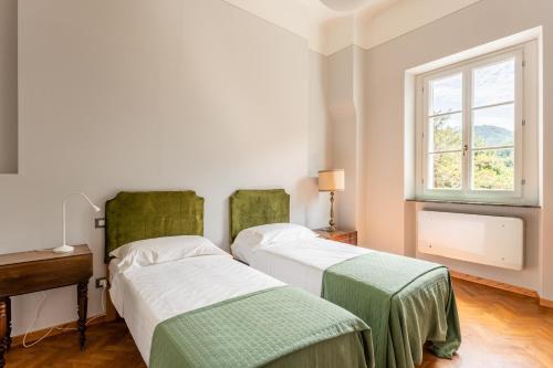 two beds in a room with a window at Villa Brecht in Bagni di Lucca