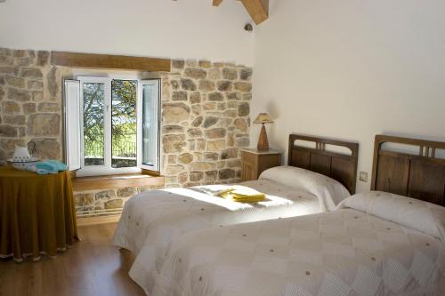 two beds in a room with a stone wall at Casa del Lago de Campoo in Orzales