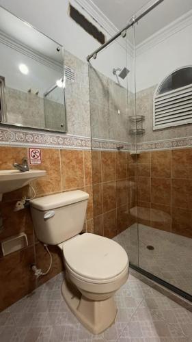 a bathroom with a toilet and a glass shower at Hotel Manoa in Cúcuta
