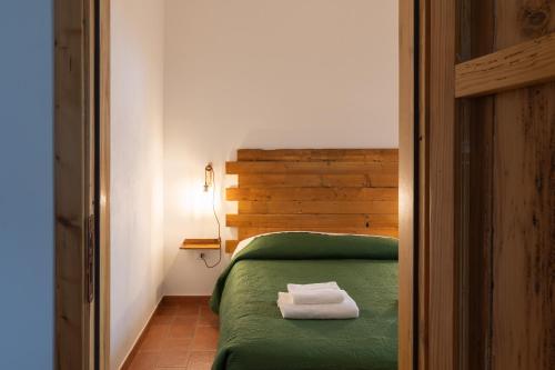 a bedroom with a green bed with two towels on it at Casa delle Pigne in Camporeale