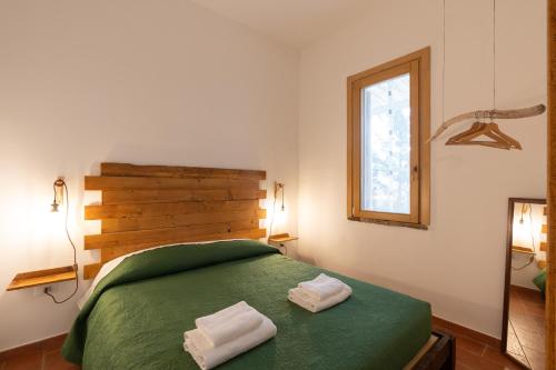 a bedroom with a green bed with two towels on it at Casa delle Pigne in Camporeale