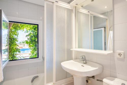 a white bathroom with a sink and a window at Villa Quesada in Paguera