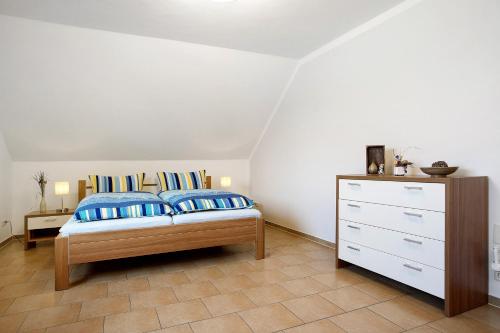 a bedroom with a bed with blue pillows and a dresser at Ferienwohnung Bella in Fuhlendorf